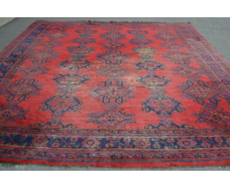 A Turkish carpet, blue  geometric designs on a red ground.  424cm long x 366cm wide.