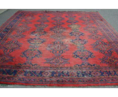 A Turkish carpet, blue  geometric designs on a red ground.  424cm long x 366cm wide.