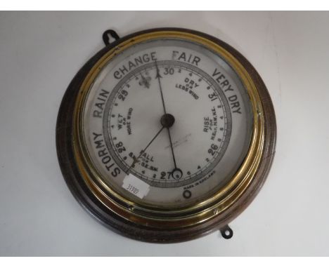A circular brass barometer mounted on board 