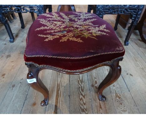 A Victorian upholstered and embroidered stool on four cabriole legs.