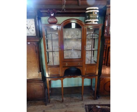 An Edwardian mahogany and inlaid display cabinet, the central glazed panel under a domed top flanked by glazed doors, above a