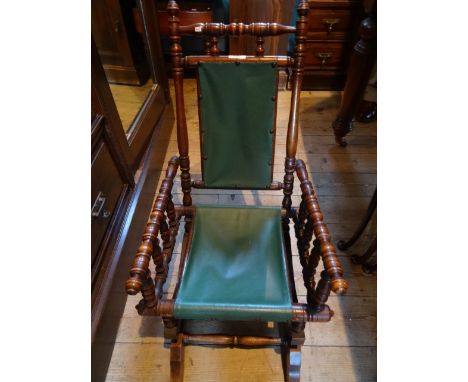 A child's bobbin rocking chair with green leather back and seat.