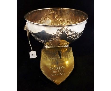 A large silver plated punch bowl with twin lion mask ring handles and floral decoration in relief, over a reeded circular bas