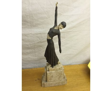 An Art Deco style figurine of a lady wearing a pleated skirt, bolero jacket and a turban: she stands on a marble base with ou