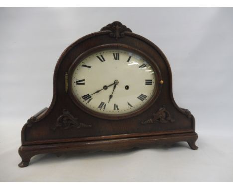An Edwardian oak cased mantle clock, unusually with an oval enamel dial, 18" w.