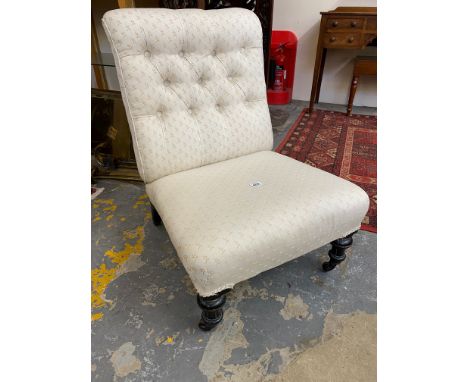 A late Victorian button back upholstered nursing chair raised upon ebonised supports to castors. 