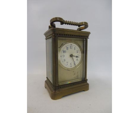 A brass carriage clock with engine turned decoration and white enamel dial with blue numerals.