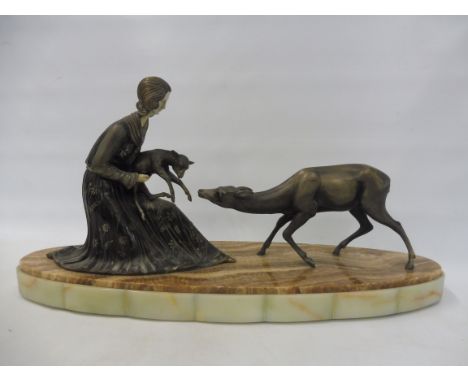 An Art Deco table top figure group of a lady holding a doe with a standing deer  beside, sat on an oval base, 28" long.