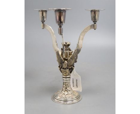 A silver parcel gilt three branch candelabra, shaped arms, on rampant bat, griffin and eagle supports, each with shields, cen