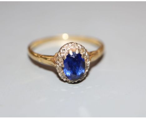 An 18ct, synthetic sapphire and diamond set oval cluster ring, size T, gross 3.2 grams.CONDITION: Needs a good clean. Wear to