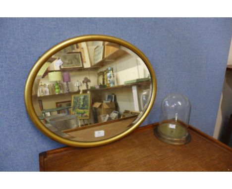 A Victorian gilt framed oval mirror and a glass dome 