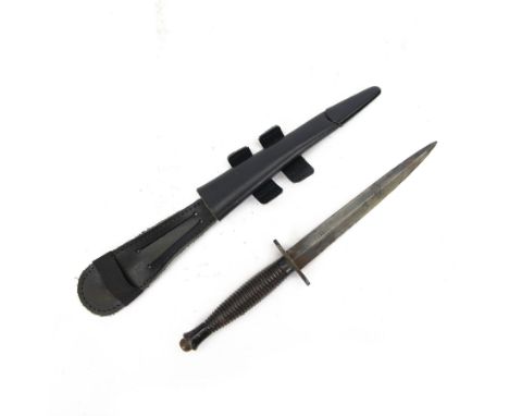 British commando knife, with ribbed ebonised steel hilt with a blued stiletto blade marked, with leather scabbard, blade 18cm