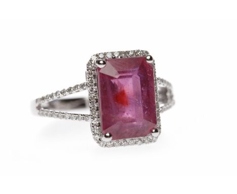 FOURTEEN CARAT WHITE GOLD RUBY AND DIAMOND DRESS RINGthe emerald cut ruby 10.7mm long and within a diamond border, on bifurca