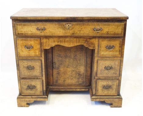 A Georgian style cross banded and figured walnut veneered kneehole desk, 20th CenturyThe rectangular top with rounded front e