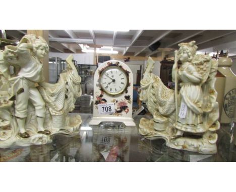 A pair of porcelain figures and a china mantel clock.