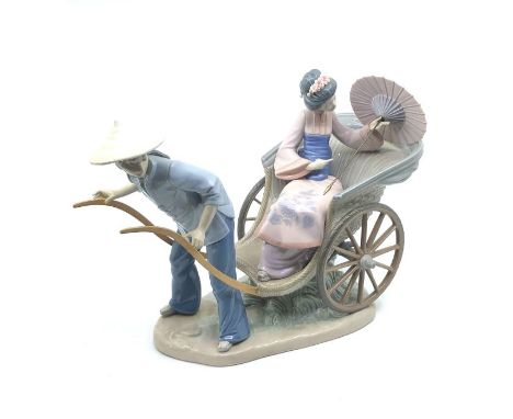 A 20th century Lladro ceramic figurine of an oriental lady with a fan (detached) in a cart pulled by a man, on a base (one wh