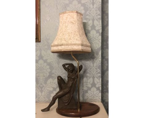 A mid 20th century art deco lamp, with shade on a metal column on an oval wooden base, the reclining art deco figure loose fr