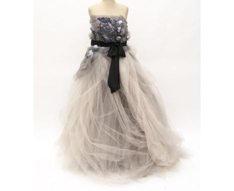 Designer evening gown in shades of grey. The skirt has layers of tulle with organza petals trailing over the hip topped with 