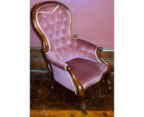 A Victorian mahogany nursing arm chair, circa 1870, scrolling spoon back with button back upholstery, scrolling arms, raised 