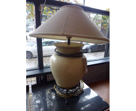 A contemporary fine art table lamp sitting in a metal stand, having fabric shade and crackled effect to lamp base.