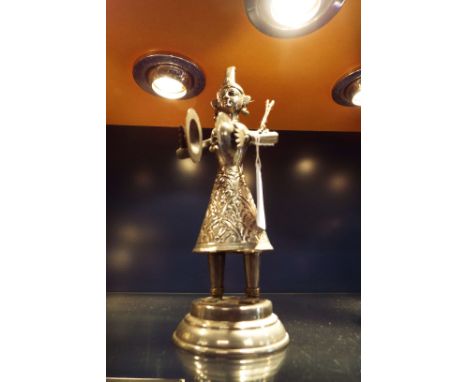 A white metal figure of a female musician with applied bells playing cymbals 