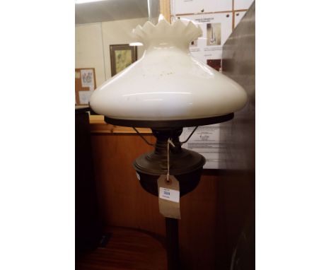 A brass oil lamp with opaque glass shade