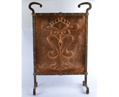 An early 20th Century Art Nouveau style wrought iron and beaten copper fire screen, of rectangular form, raised upon four fee