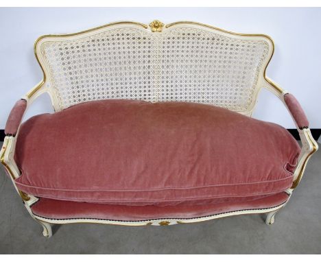 A contemporary continental style settee, cane back, padded arms, the seat upholstered in a pink fabric with a matching loose 