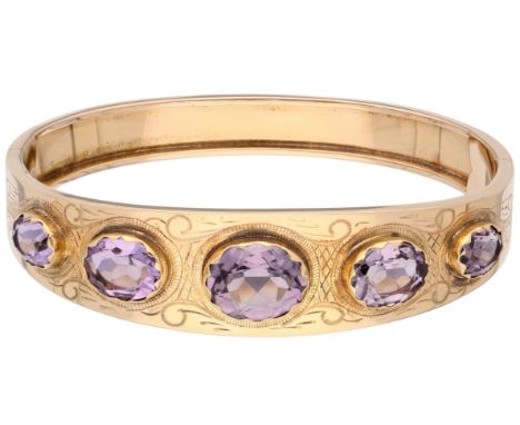 14K Yellow gold bangle bracelet set with approx. 10.49 ct. amethysts. The bangle features engraved details. Set with five ova