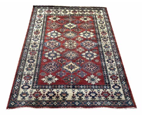 KAZAK RUG, 175cm x 128cm, scattered geometric amulates on a ruby field within corresponding borders.