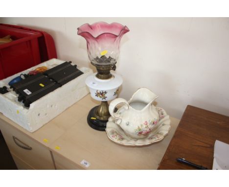 An oil lamp with cranberry glass shade together with a wash jug and bowl&nbsp;