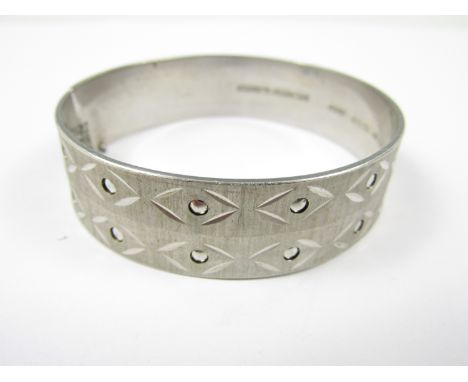 A mid 20th Century hinged bangle, having a bright-cut and punched geometric design running over a brushed face, 29.8g