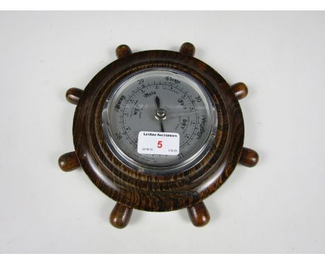 A carved oak ship's wheel barometer