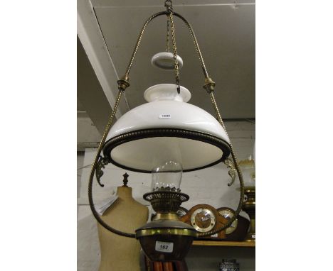 A brass framed hanging oil lamp complete with shade, smut collector and chimney.