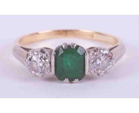 An 18ct yellow gold &amp; platinum three stone ring set with a central emerald cut emerald, approx. 0.50 carats with a round 