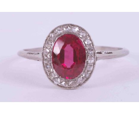 A platinum antique cluster ring set with an oval cut synthetic ruby approx. 0.75 carats surrounded by small old round cut dia
