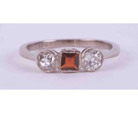 An 18ct white gold three stone ring set with a central square cut garnet, approx. 0.18 carats with an old round cut diamond s