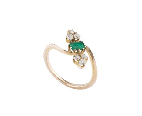 An emerald and diamond crossover ring, the rectangular step-cut emerald obliquely claw set between trios of round brilliant a