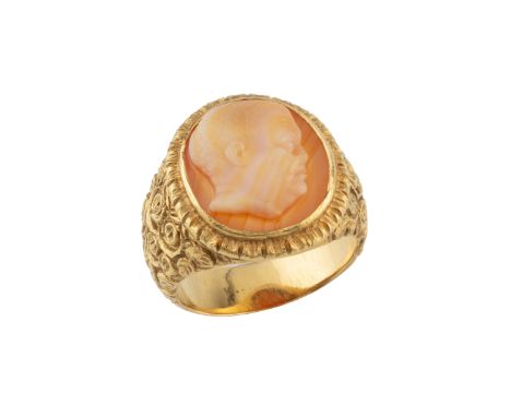 A hardstone cameo ring, the oval cameo carved with a male portrait profile, to a tapered yellow precious metal mount, decorat