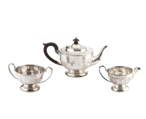A George V silver three piece tea service, of panelled circular form, the teapot with composite handle and knop, by Henry Cli