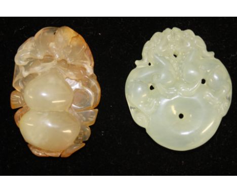 A Chinese agate pendant, carved as a gourd on scrolling foliage; and a pale green jade pendant of two dogs of fo atop a ring,