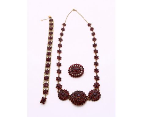 Garnet jewelry set with a brooch, choker, missing one stone, and bracelet. In good condition