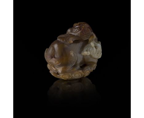 CARVED AGATE MYTHICAL BEASTQING DYNASTY, 19TH CENTURY in the form of a reclining lion dog with its head turned sideward and i