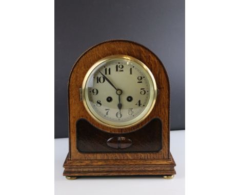 Early 20th century Domed Oak Cased Mantle Clock with beaded edge, the dial with arabic numerals, raised on four squat brass f