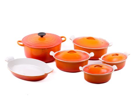 A Le Creuset set of six orange enamel cookware. Including four oval casserole dishes, an oval gratin dish and a large round t