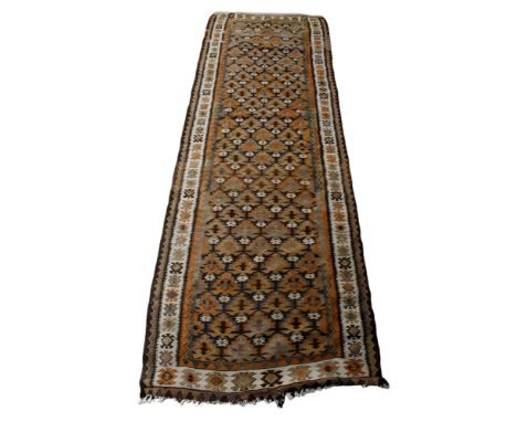 A Kilim style brown and cream runner rug. With multiple geometric borders and a repeated pattern to the central medallion. 30