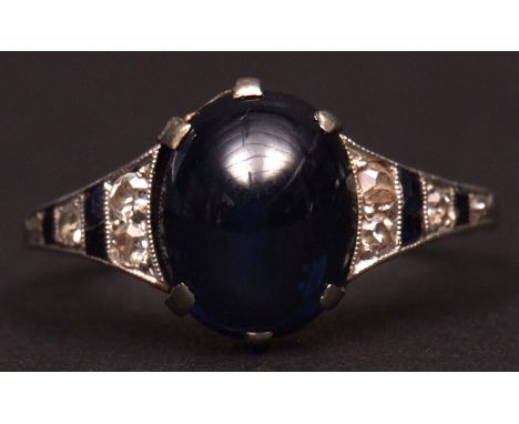 Art Deco precious metal sapphire and diamond ring, the centre oval cut cabochon sapphire claw set between tapering small diam
