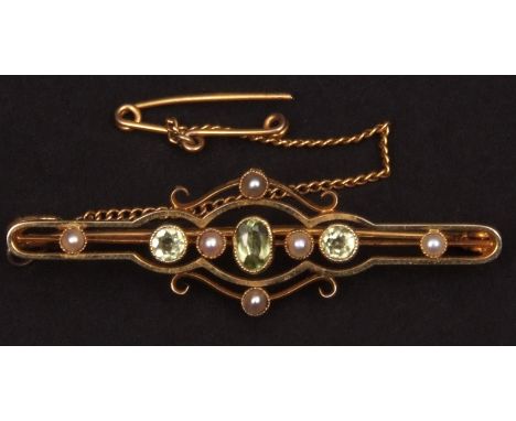 Cased Edwardian open work bar brooch, the centre set with three peridot flanked to the compass points with seed pearls, indis