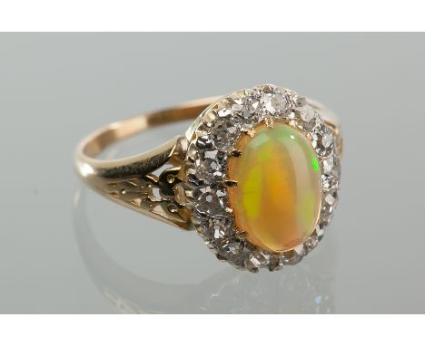 OPAL AND DIAMOND CLUSTER RING 
set with a central oval cabochon opal surrounded by brilliant cut diamonds, unmarked, size K