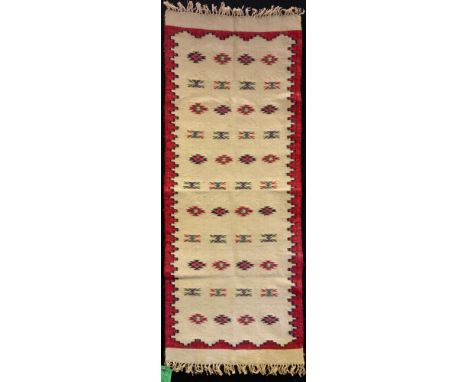 A Traditional Bulgarian Woolen carpet, woven in red and white, with a narrow crenelated border, framing a field of folk art m